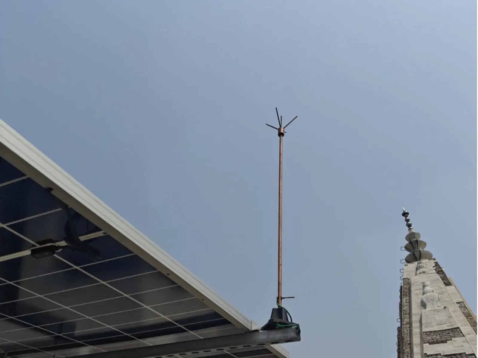 Avaada TOPCon modules on the elevated structure with a lightning arrester beside the temple spire