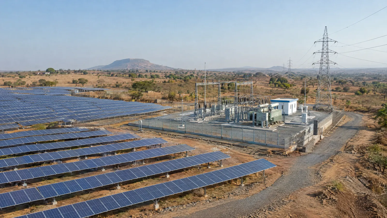 Ground-mounted solar plant in Maharashtra with a 33 kV switchyard and an overhead line carrying power toward the grid.