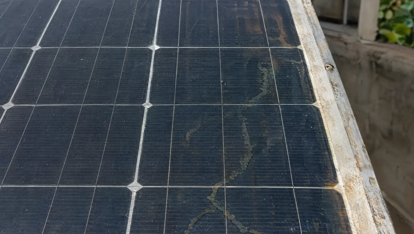 Close-up of an aged solar module surface with faint discolouration and snail-trail lines across the cells.
