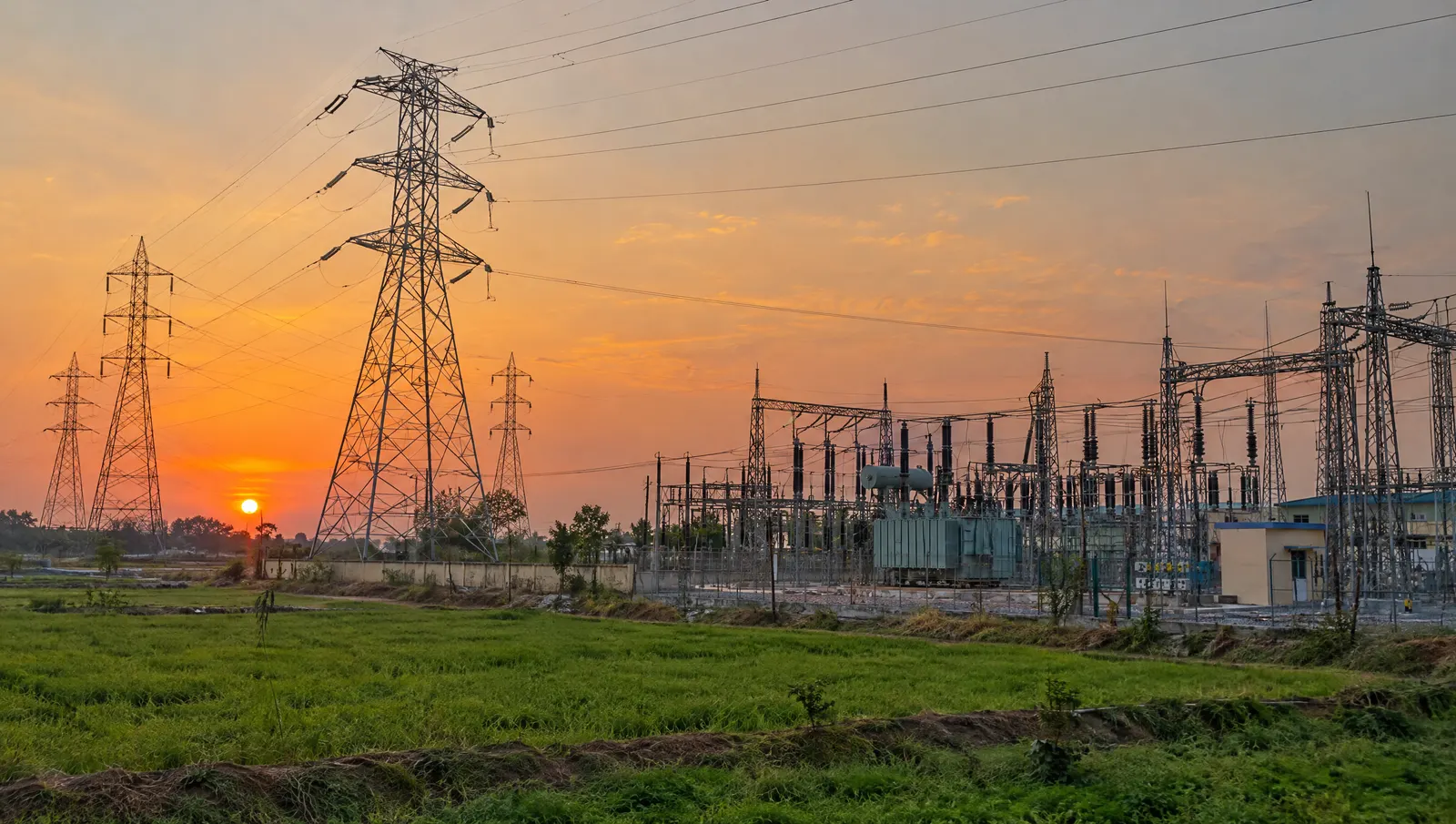 High-voltage transmission towers and a substation in rural India; under a virtual PPA, the buyer keeps drawing power from its existing grid connection.